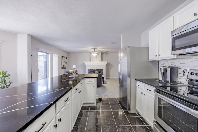 3144 Longbow Dr, Grand Prairie, TX 75052 - kitchen featuring a ceiling fan, dark countertops, appliances with stainless steel finishes, and white cabinetry