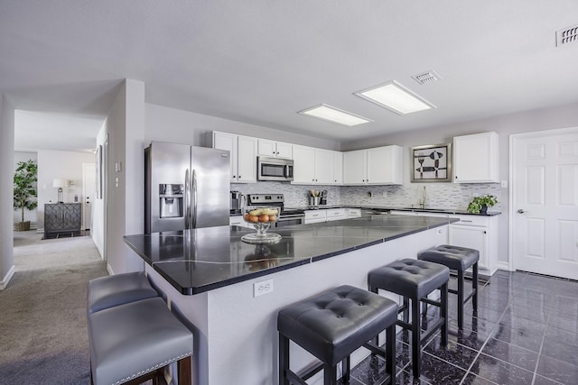 3144 Longbow Dr, Grand Prairie, TX 75052 - kitchen with a sink, appliances with stainless steel finishes, a breakfast bar, and white cabinetry