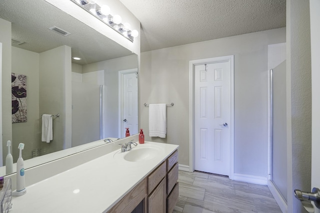 3144 Longbow Dr, Grand Prairie, TX 75052 - bathroom featuring a textured ceiling, visible vents, a shower stall, vanity, and baseboards