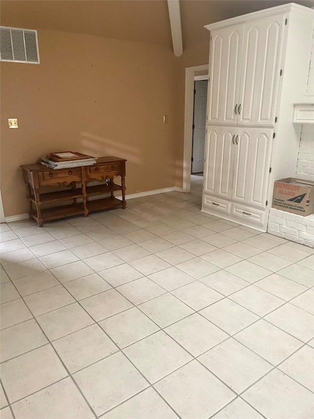 interior space featuring visible vents, baseboards, light tile patterned floors, and beamed ceiling