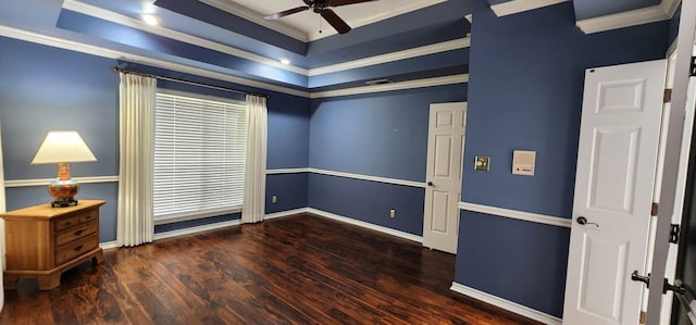spare room with crown molding, a raised ceiling, a ceiling fan, baseboards, and wood finished floors