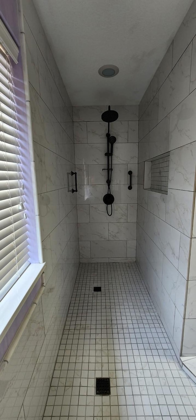 full bath featuring tile patterned floors and a tile shower