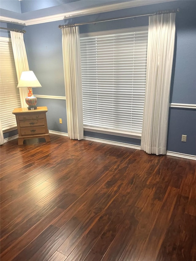 spare room with baseboards and wood finished floors