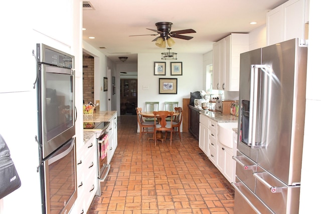7650 Shade Tree Ln, Celina, TX 75009 - kitchen featuring stainless steel appliances, brick patterned flooring, white cabinets, a ceiling fan, and light stone countertops