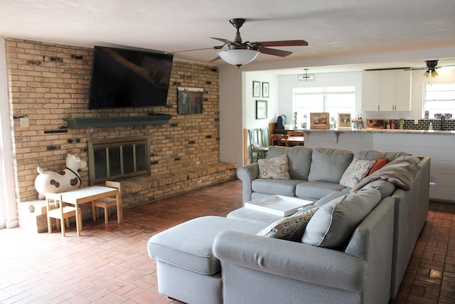 7650 Shade Tree Ln, Celina, TX 75009 - living room featuring a ceiling fan, brick floors, a fireplace, and brick wall