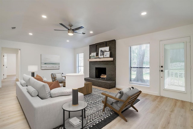 living area featuring ceiling fan, a fireplace, light wood-type flooring, and visible vents