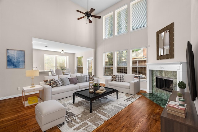 5921 Colby Dr, Plano, TX 75094 - living area featuring baseboards, a tiled fireplace, ceiling fan, wood finished floors, and a towering ceiling
