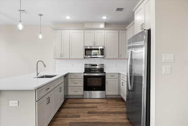 525 Galt Dr, Stephenville, TX 76401 - kitchen with dark wood-type flooring, a peninsula, tasteful backsplash, a sink, and stainless steel appliances