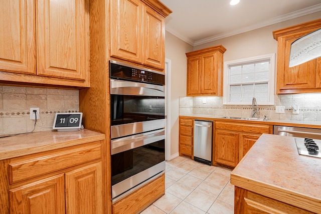 kitchen featuring ornamental molding, light countertops, light tile patterned flooring, stainless steel appliances, and a sink