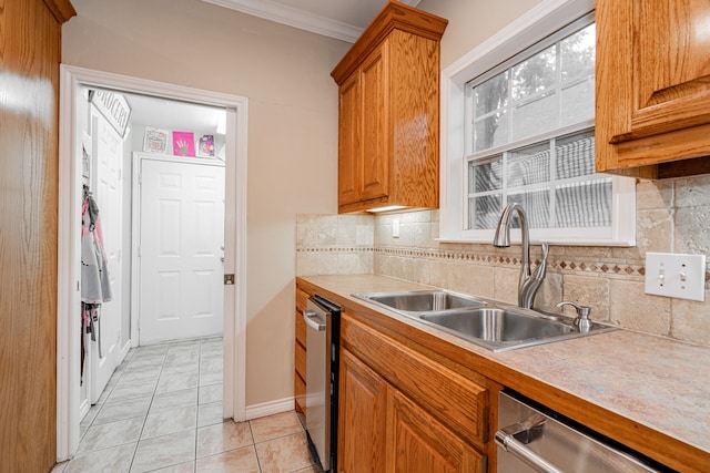 kitchen featuring light countertops, stainless steel dishwasher, a sink, and brown cabinetry