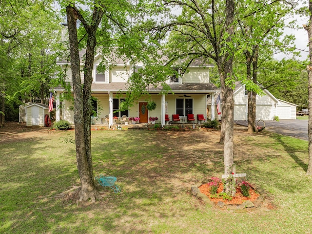 view of front of house with a front yard, a storage shed, a porch, a garage, and an outbuilding
