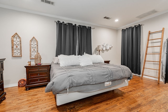 bedroom featuring visible vents, crown molding, and light wood-style flooring