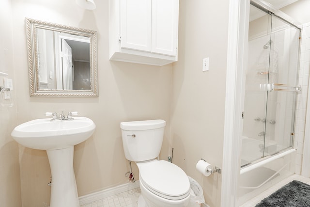 full bath featuring baseboards, a sink, toilet, shower / bath combination with glass door, and tile patterned flooring