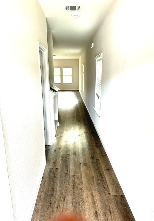 hall featuring baseboards, dark wood finished floors, and visible vents