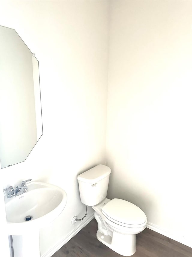 bathroom with baseboards, a sink, toilet, and wood finished floors