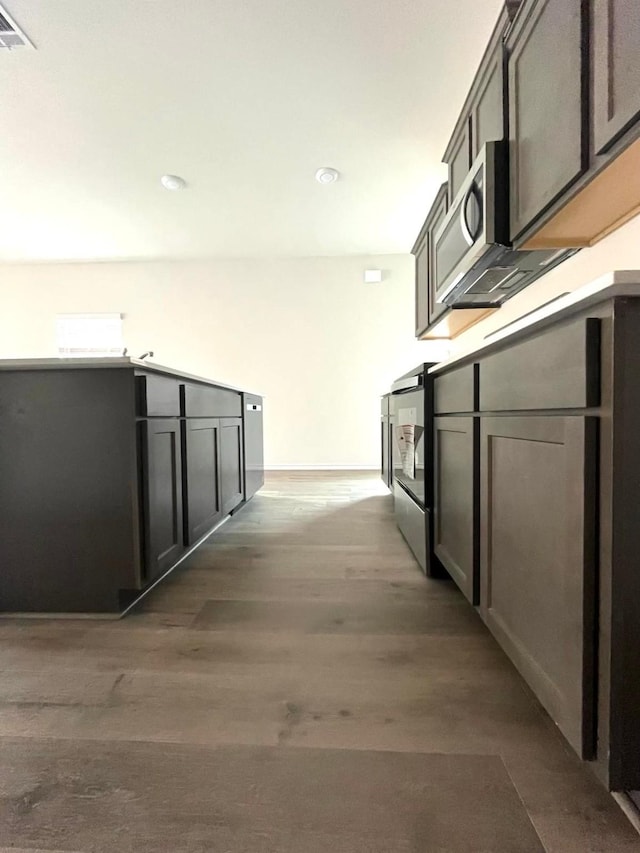 kitchen with visible vents, baseboards, wood finished floors, and stove