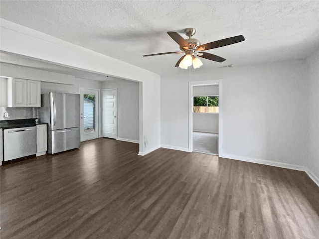 1209 Sylvan Dr, Garland, TX 75040 - unfurnished living room with dark wood-type flooring, baseboards, ceiling fan, and a textured ceiling