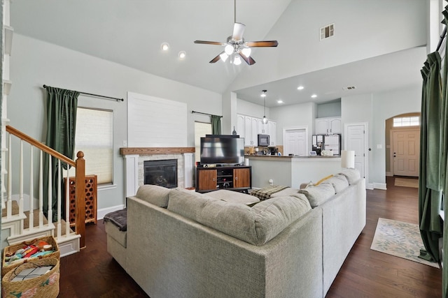 1236 Spanish Moss Dr, Savannah, TX 76227 - living room featuring stairway, a ceiling fan, a glass covered fireplace, dark wood-type flooring, and high vaulted ceiling