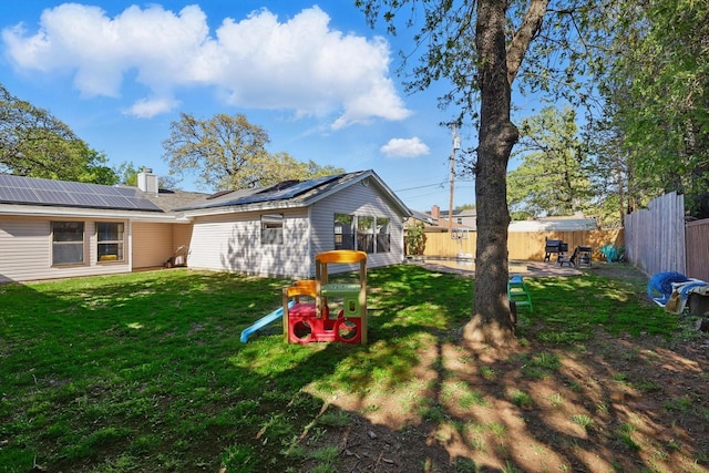 1119 Mockingbird Dr, Grapevine, TX 76051 - rear view of house featuring a lawn, a fenced backyard, roof mounted solar panels, and a chimney