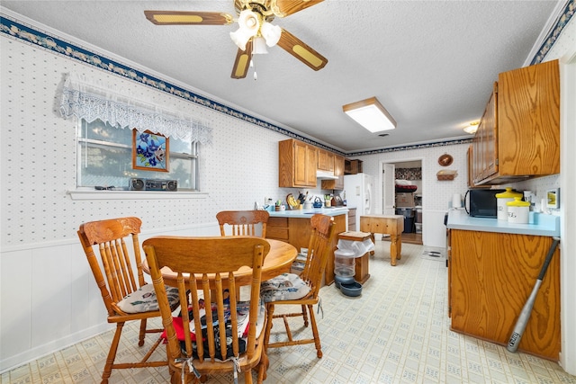 2107 Elizabeth Dr, Brownwood, TX 76801 - dining area with a textured ceiling, wallpapered walls, light floors, and a wainscoted wall