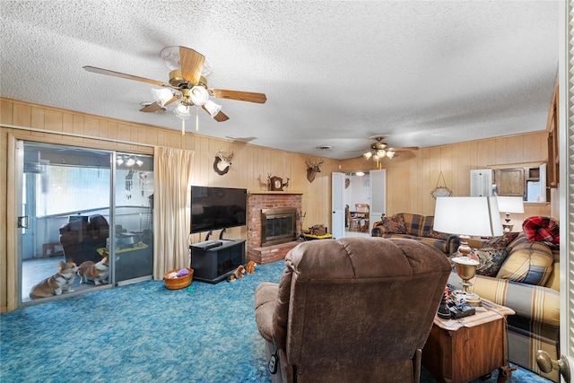 2107 Elizabeth Dr, Brownwood, TX 76801 - carpeted living area featuring wooden walls, a brick fireplace, a textured ceiling, and a ceiling fan