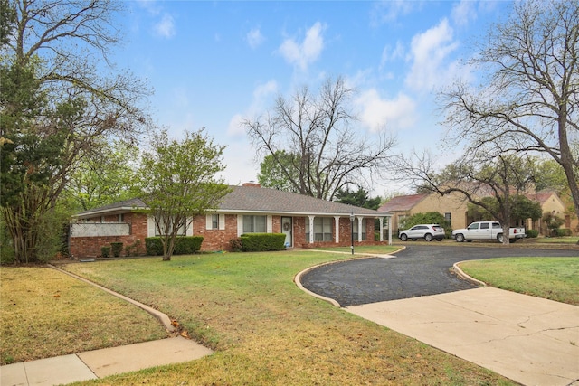 2107 Elizabeth Dr, Brownwood, TX 76801 - view of front of home with brick siding, a chimney, a front lawn, and aphalt driveway