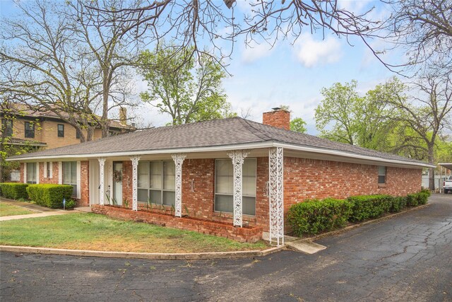 2107 Elizabeth Dr, Brownwood, TX 76801 - view of side of home featuring brick siding, a lawn, and a chimney