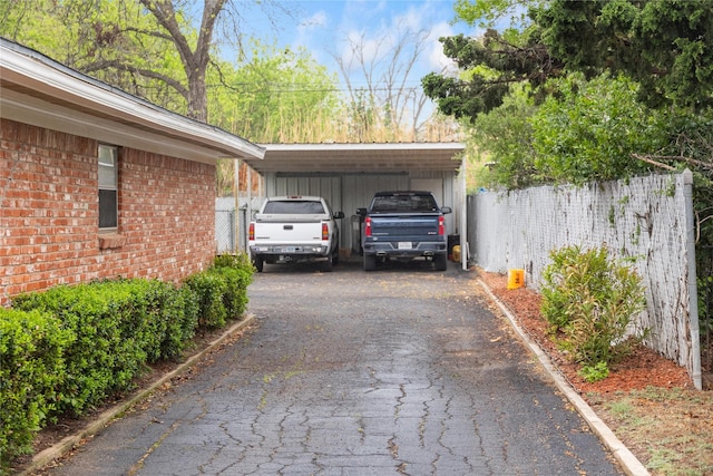2107 Elizabeth Dr, Brownwood, TX 76801 - garage featuring a carport, driveway, and fence