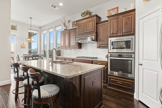 1036 Wedgewood Dr, Forney, TX 75126 - kitchen featuring stainless steel appliances, a sink, dark wood finished floors, a kitchen island with sink, and tasteful backsplash