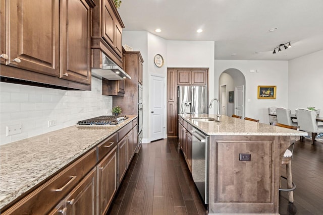 1036 Wedgewood Dr, Forney, TX 75126 - kitchen with a sink, appliances with stainless steel finishes, arched walkways, light stone countertops, and a breakfast bar