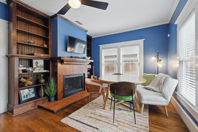 living area featuring a healthy amount of sunlight, ornamental molding, visible vents, and a tile fireplace