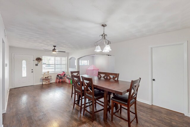 dining room with arched walkways, ceiling fan, baseboards, and dark wood finished floors