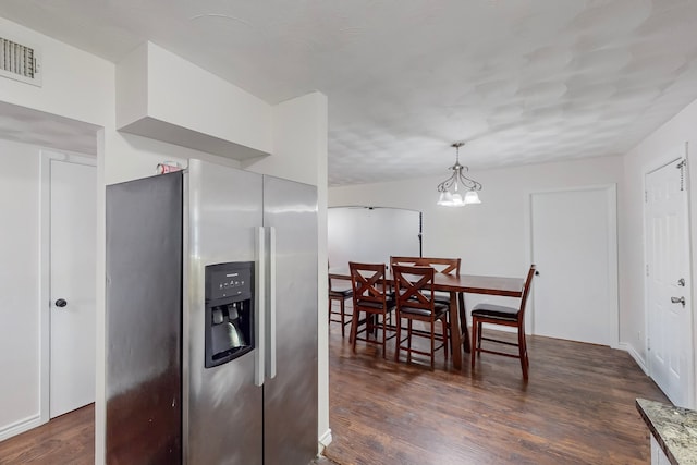 dining space featuring dark wood-type flooring, an inviting chandelier, and visible vents