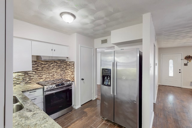 kitchen featuring ventilation hood, visible vents, dark wood-style flooring, stainless steel appliances, and decorative backsplash