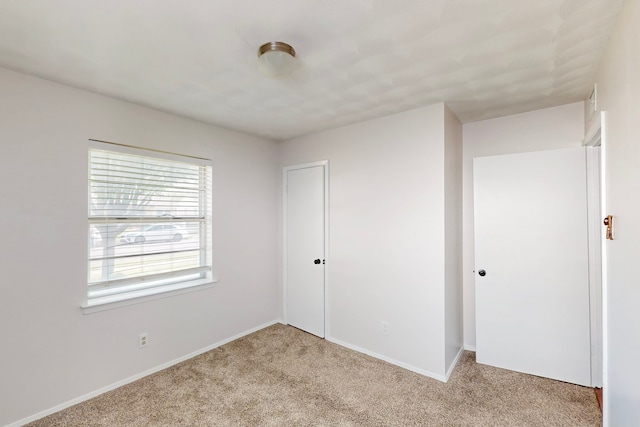 unfurnished bedroom featuring a closet, light colored carpet, and baseboards