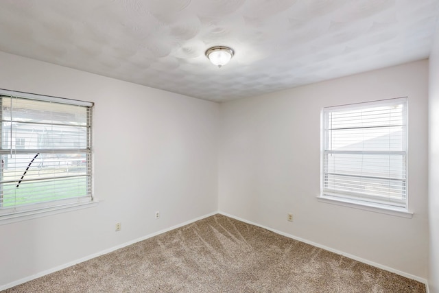 empty room with light carpet, plenty of natural light, and baseboards