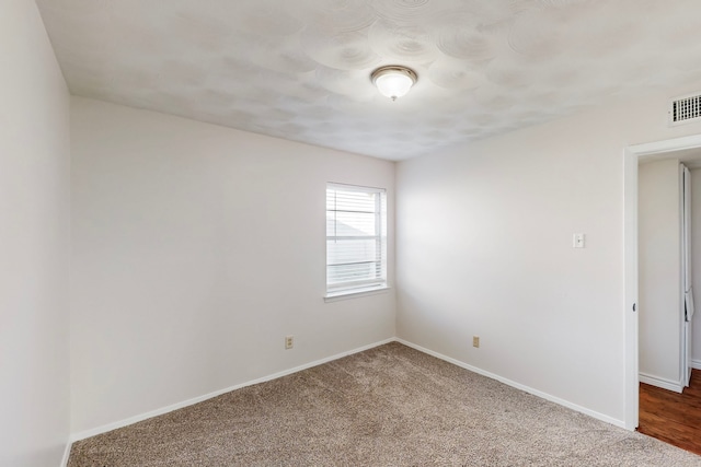 carpeted empty room featuring baseboards and visible vents