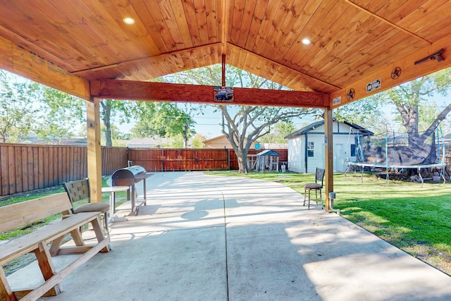 view of patio / terrace featuring an outbuilding, a fenced backyard, a trampoline, and a storage shed