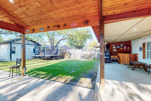view of patio featuring a trampoline and fence