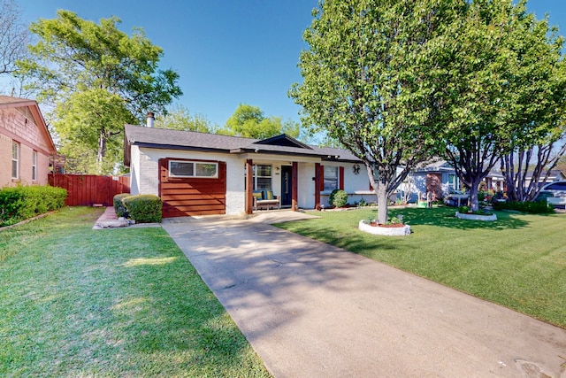 ranch-style home featuring roof with shingles, driveway, a front yard, brick siding, and fence