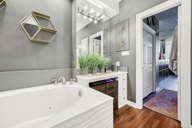 full bathroom with a jetted tub, vanity, and wood finished floors