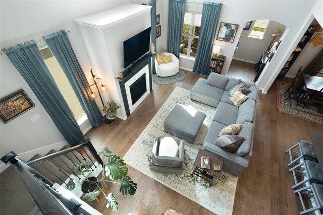 living area with arched walkways, baseboards, and wood finished floors