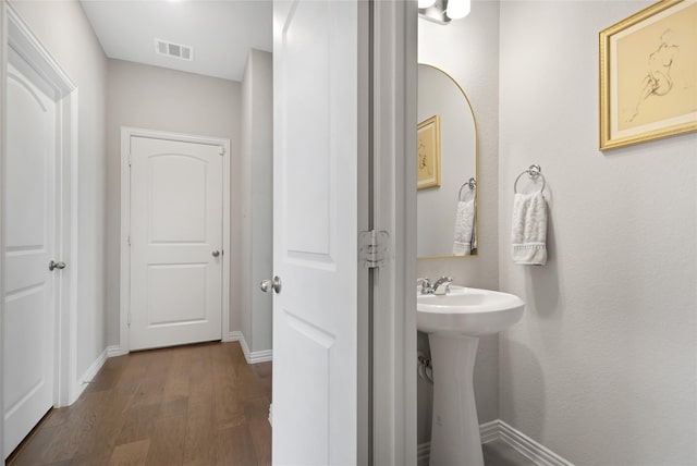 bathroom featuring wood finished floors, a sink, baseboards, and visible vents
