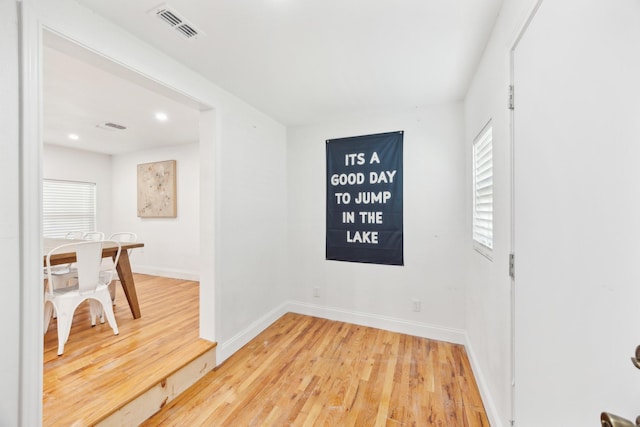 empty room with visible vents, baseboards, light wood finished floors, and a wealth of natural light