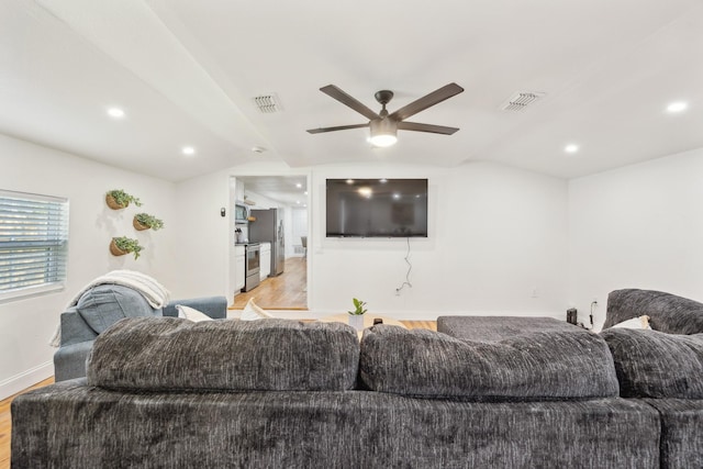 living room with light wood-type flooring, ceiling fan, vaulted ceiling, and visible vents
