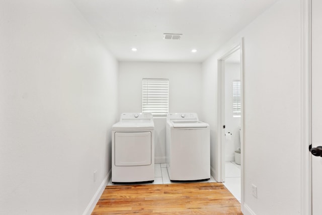 laundry room featuring light wood-type flooring, baseboards, visible vents, washer and clothes dryer, and laundry area