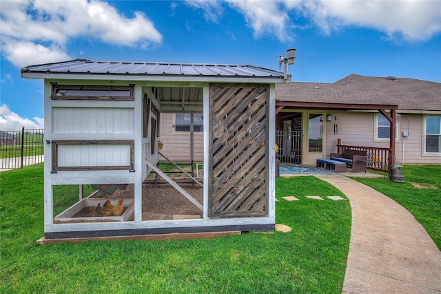 rear view of property featuring a lawn, an outbuilding, fence, metal roof, and exterior structure