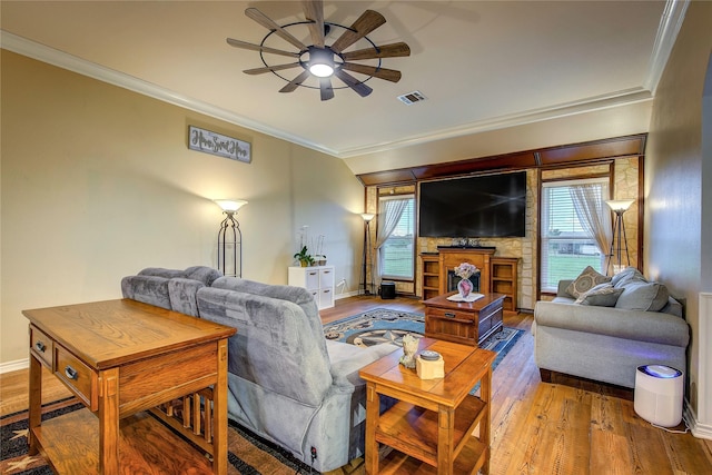 living room featuring wood finished floors, visible vents, ceiling fan, crown molding, and baseboards
