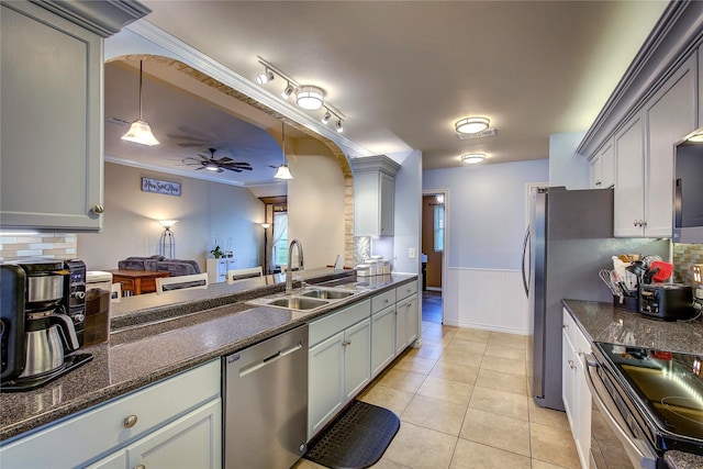 kitchen with light tile patterned floors, a sink, ceiling fan, appliances with stainless steel finishes, and decorative backsplash