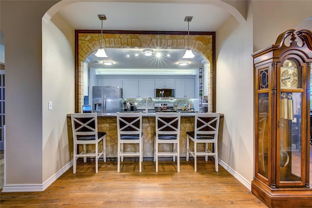 dining space with arched walkways, baseboards, and wood finished floors